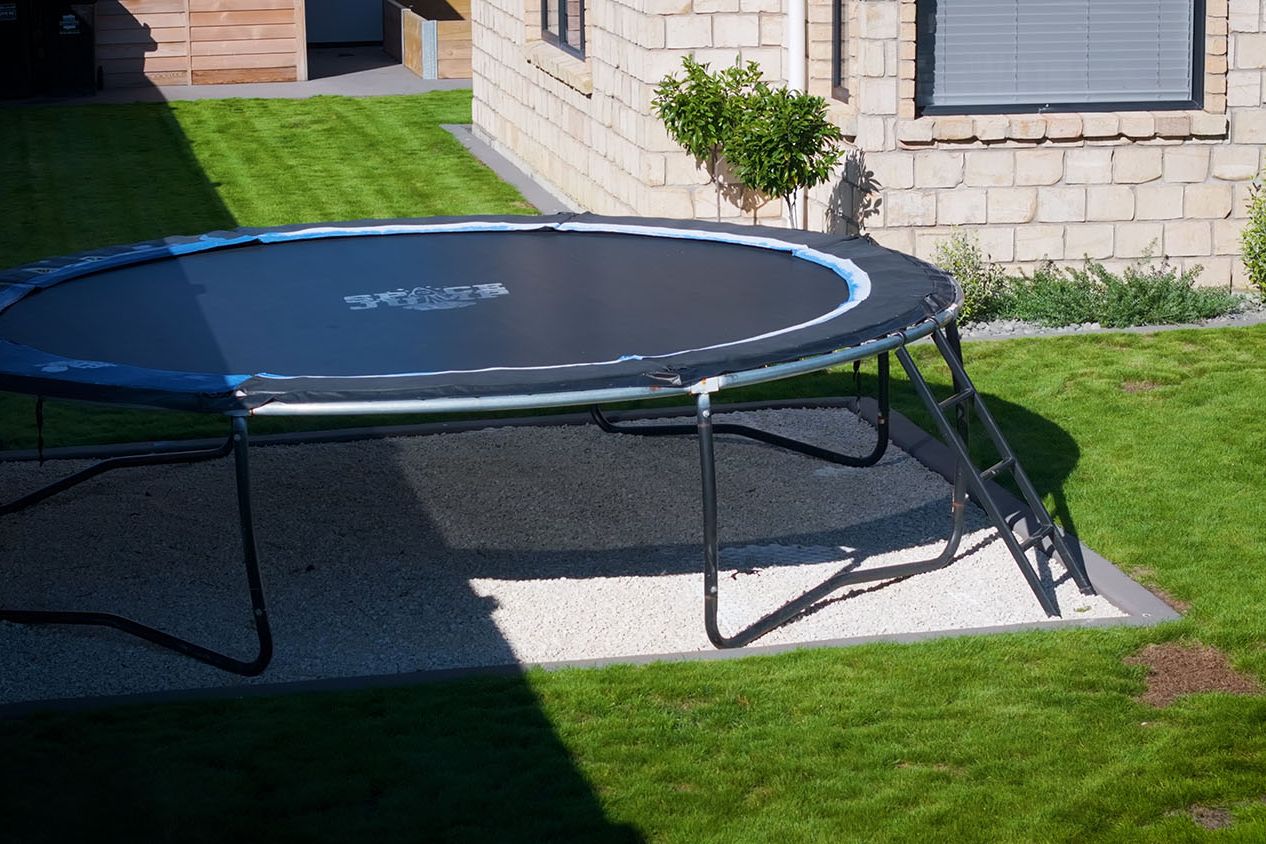 Round trampoline set on a level permeable paved base in a backyard lawn