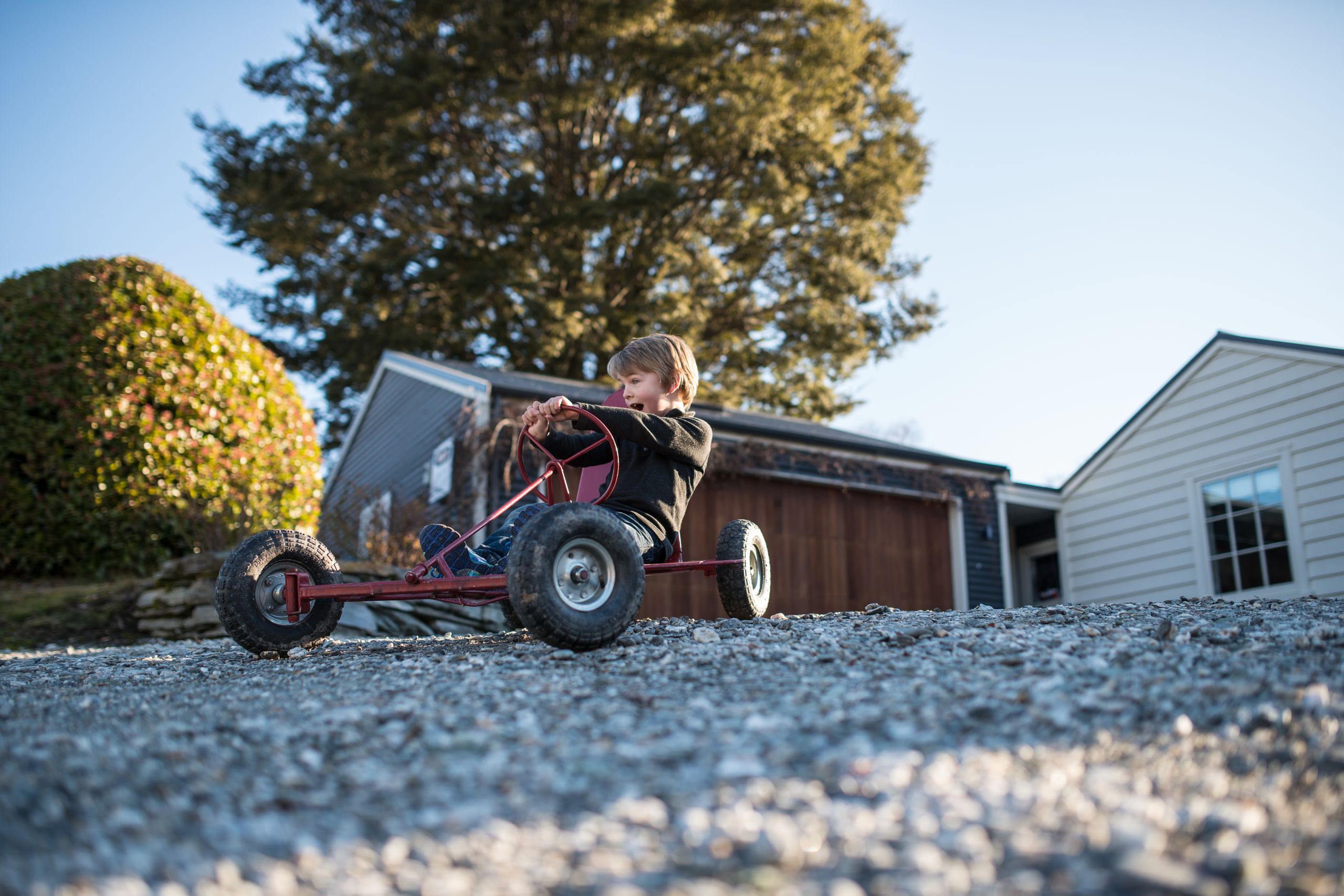 Child driving a go-kart across a firm gravel driveway