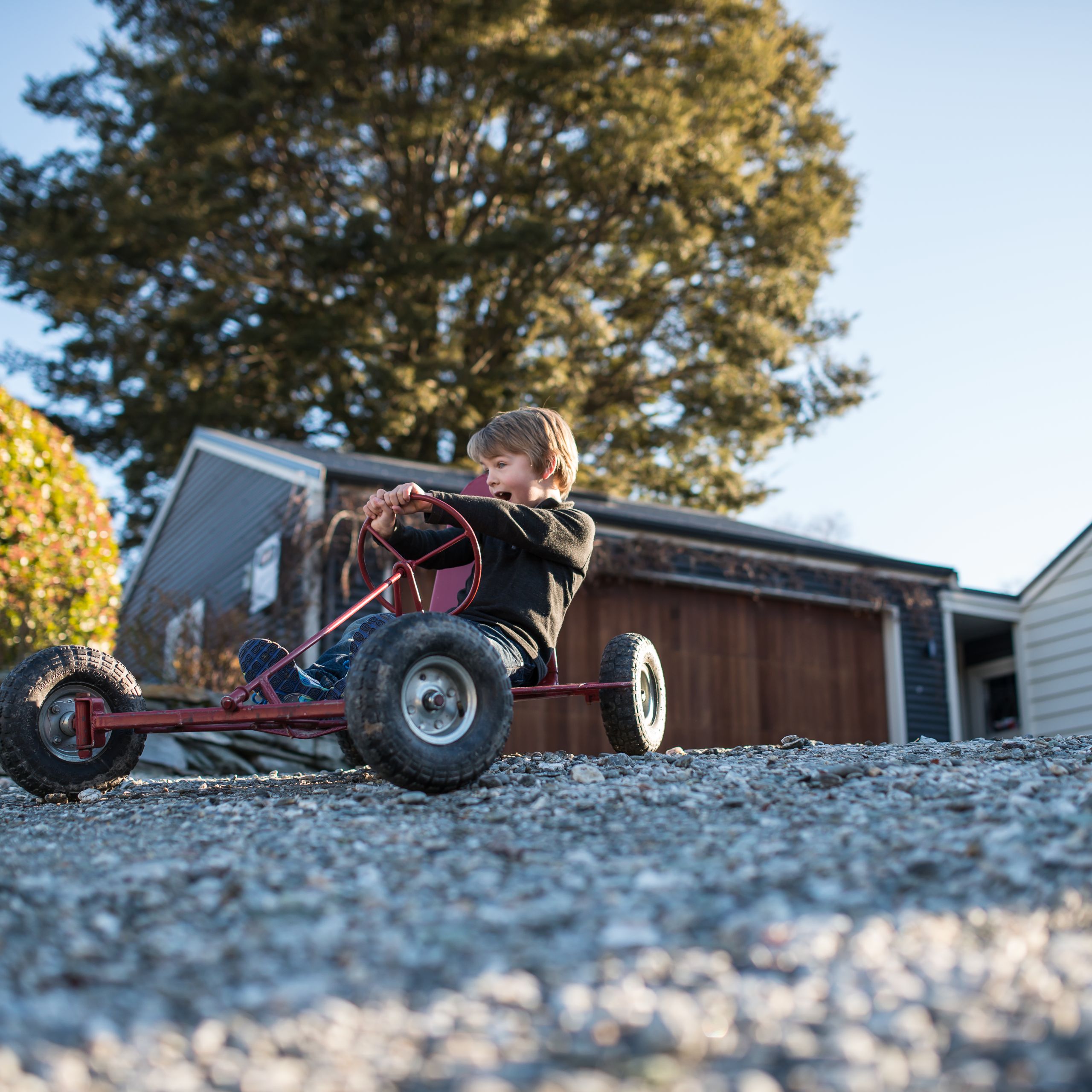 Child driving a go-kart across a firm gravel driveway