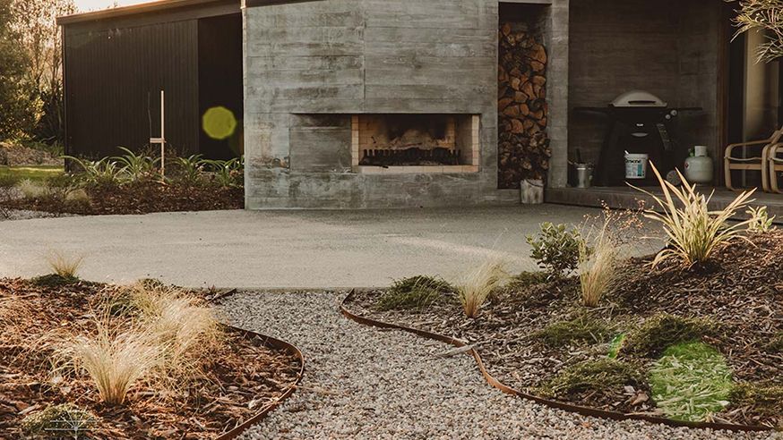 Outdoor fireplace and gravel courtyard with native grasses