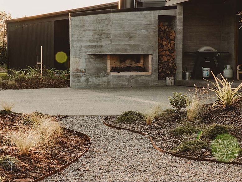 Outdoor fireplace and gravel courtyard with native grasses