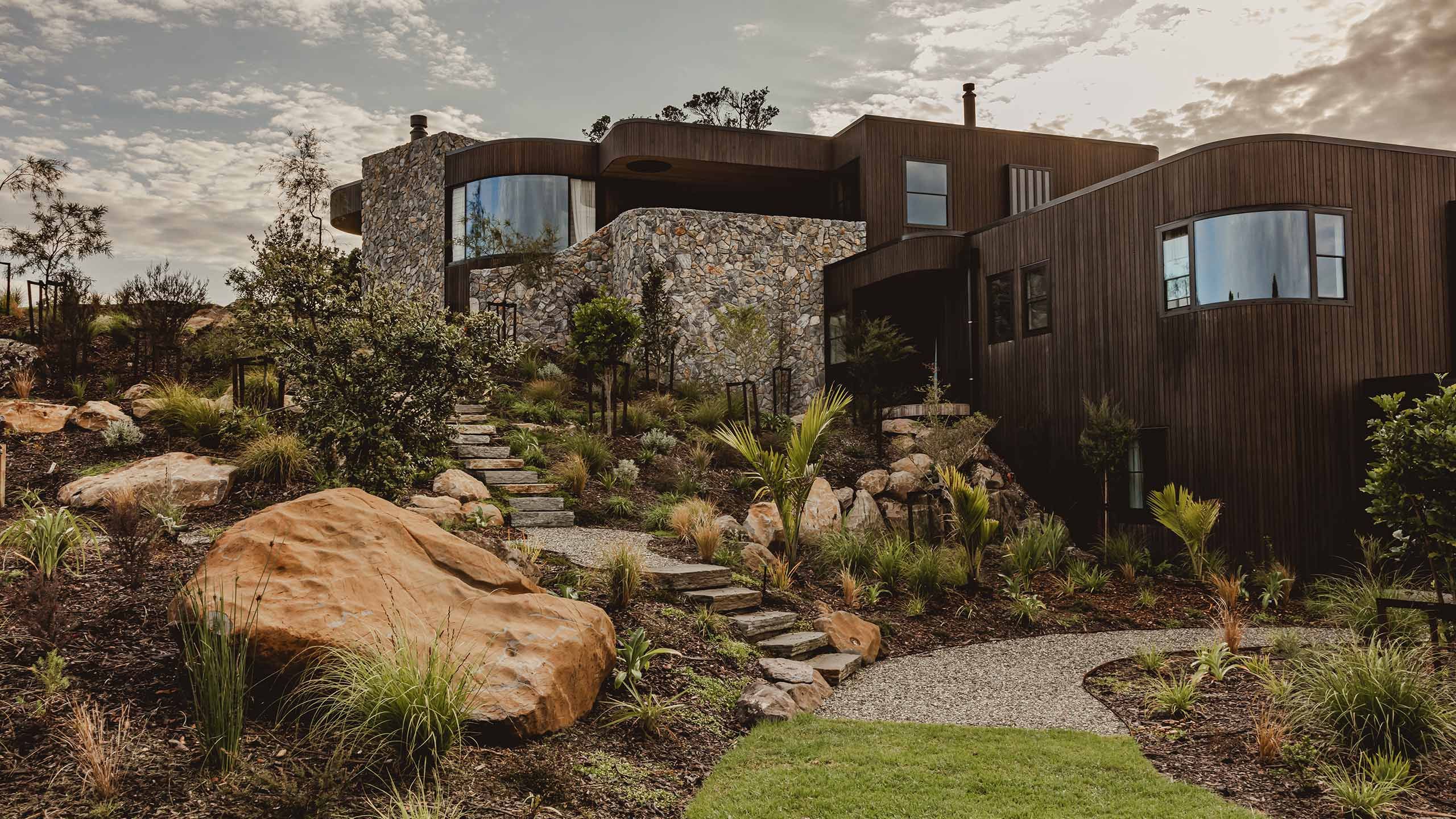Modern home with landscaped gravel paths, boulders and native planting